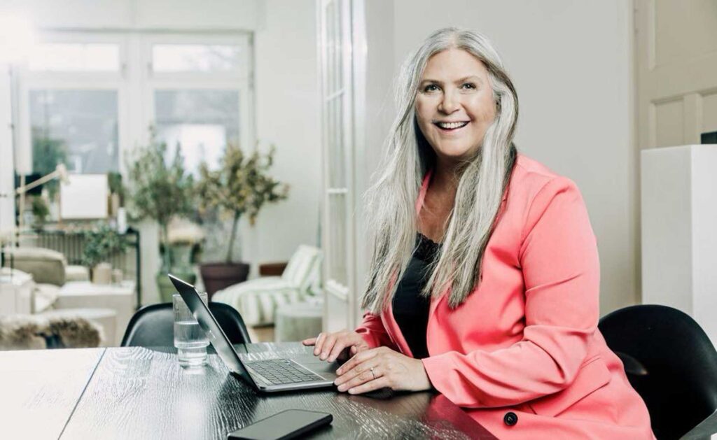 Jasminka am Schreibtisch mit einem rosafarbenen Anzug