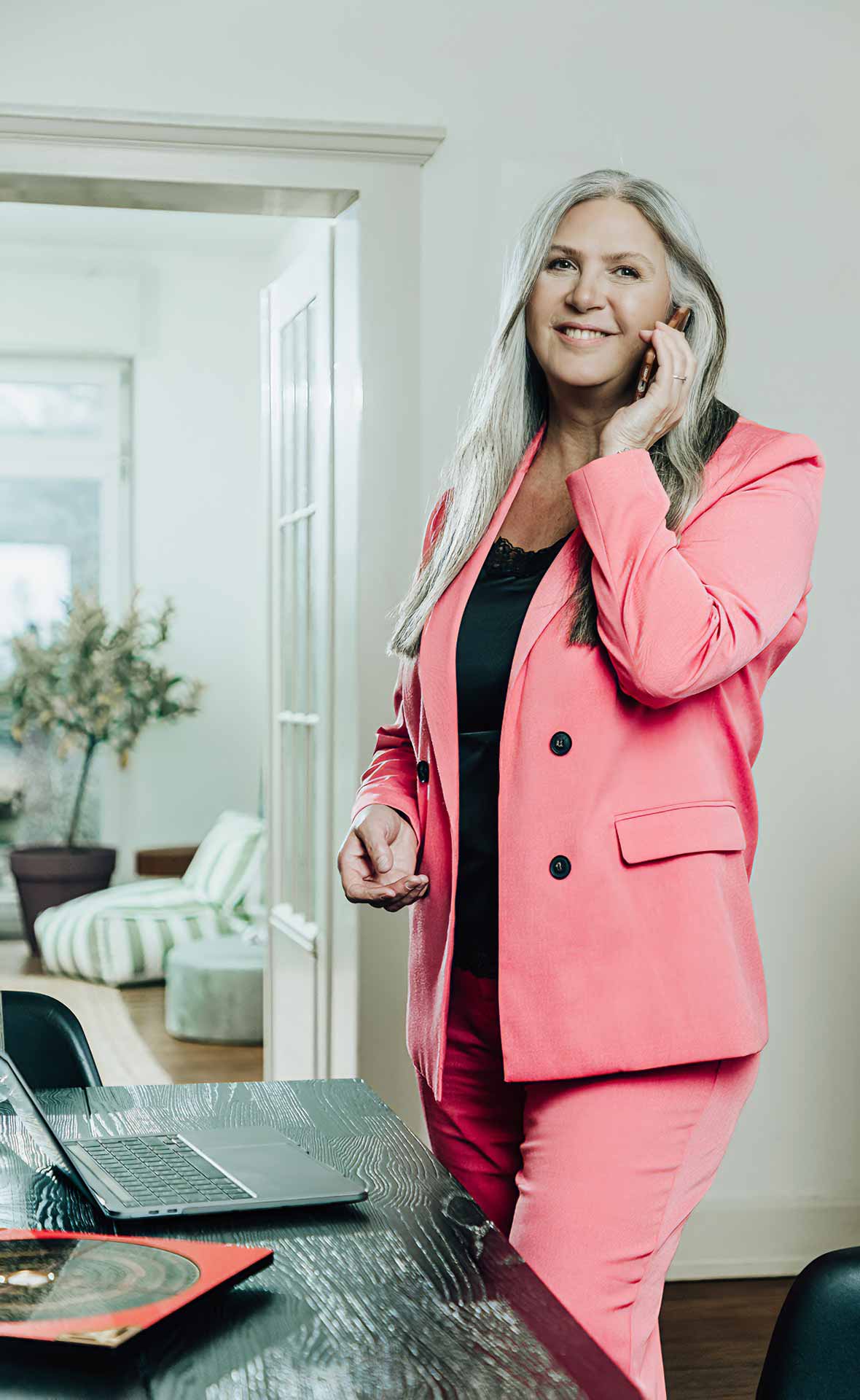 Jasminka stehend am Schreibtisch mit Handy